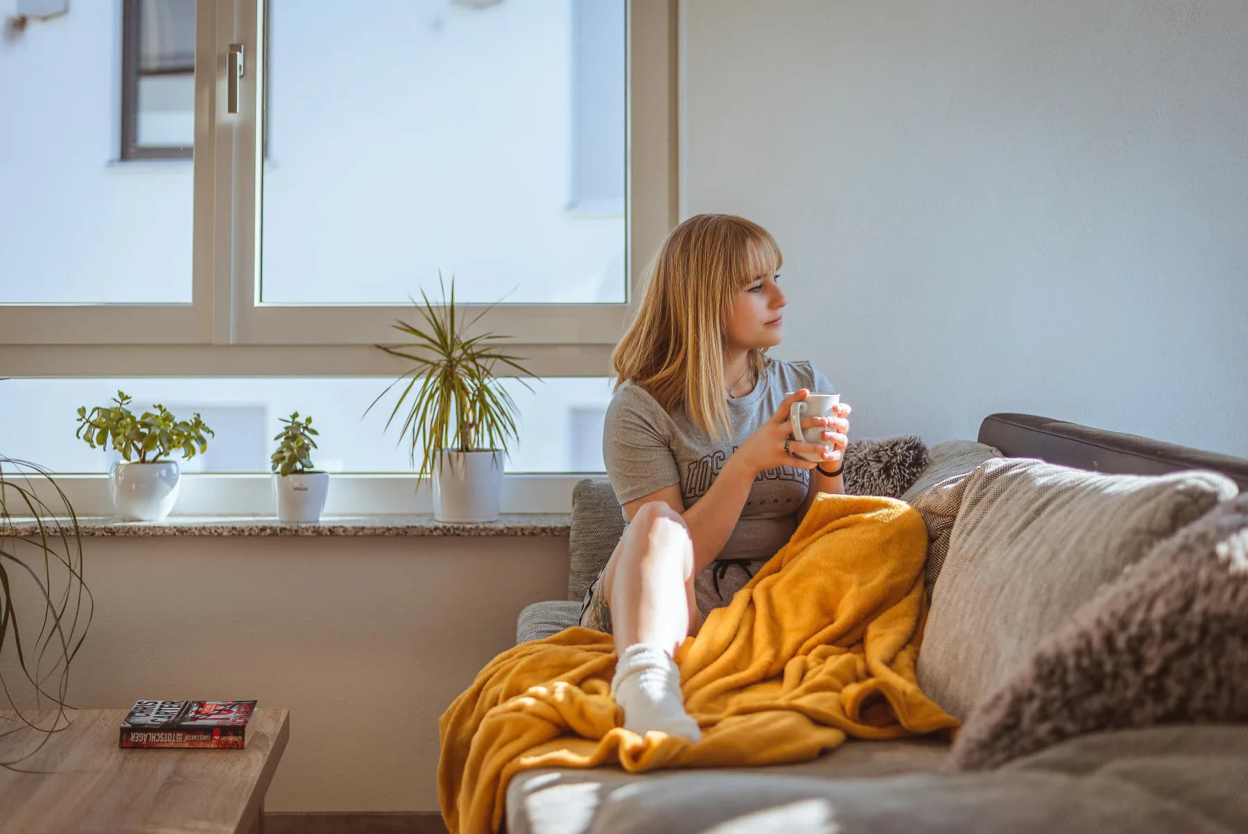 Ettertenksom person med kaffe ved vinduet som vurderer økonomien